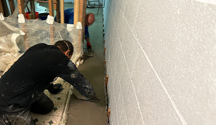 Professional workers waterproofing a basement