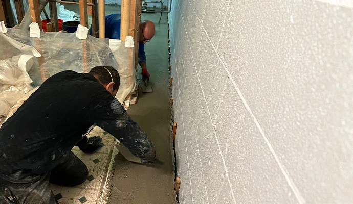 Professional workers waterproofing a basement