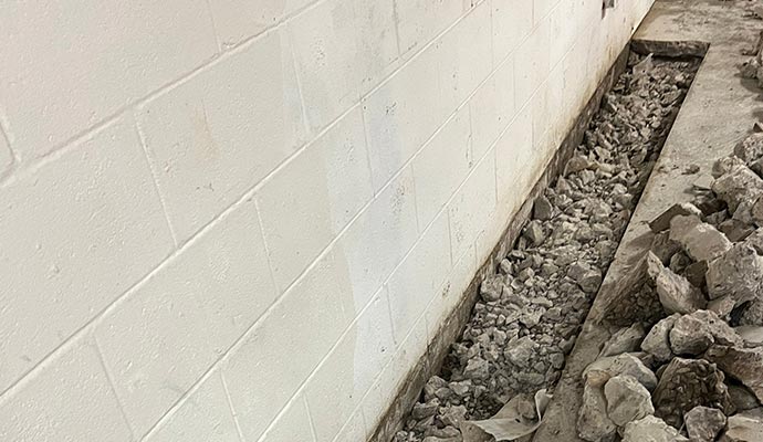 A trench filled with gravel for a basement interior drainage system installation