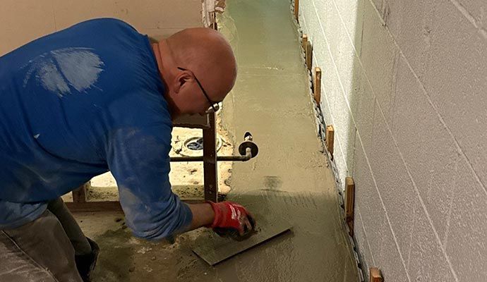 Expert repairing a damaged basement floor using professional tools