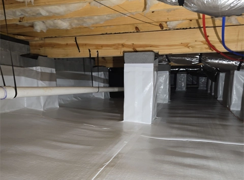 A clean, encapsulated crawl space with white moisture barrier laid over the ground and up the foundation walls.