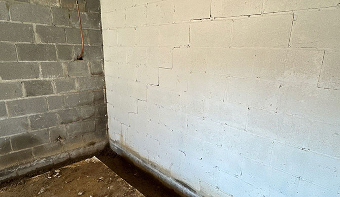 Basement corner showing structural crack and damaged flooring