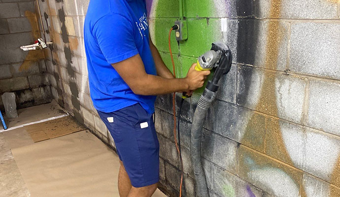 Wall repair in progress with grinder and dust collection equipment