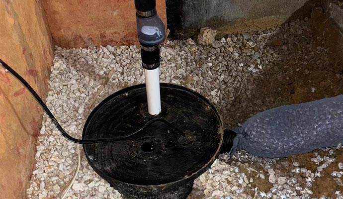 A round black sump pump basin installed in an excavation area 